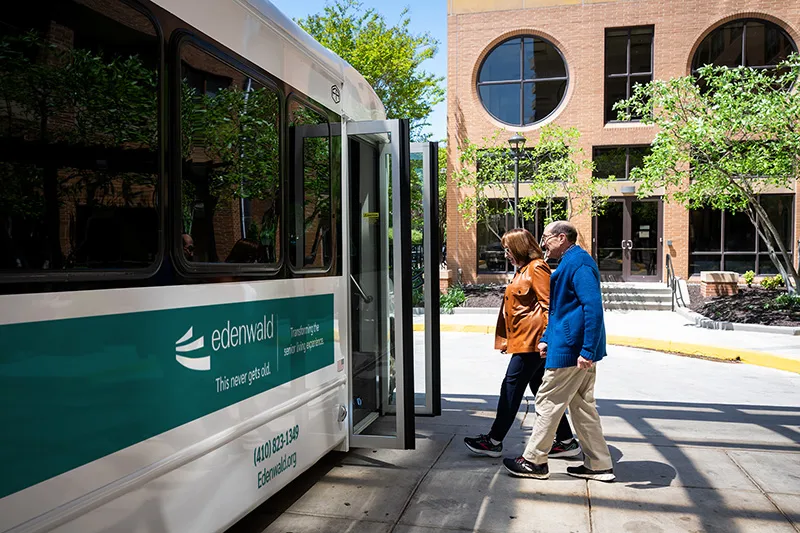 Two seniors walking onto an Edenwald Senior Living bus