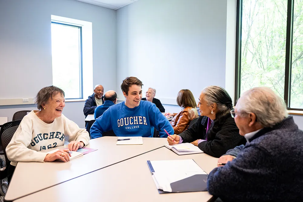 An older man and two women sitting with a college student in a classroom