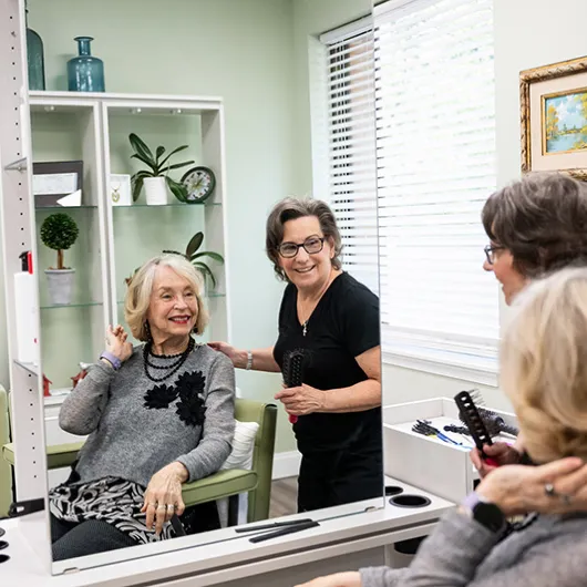 Edenwald_Residential-Services-Amenities_1 A woman smiling looking at her new haircut in a mirror