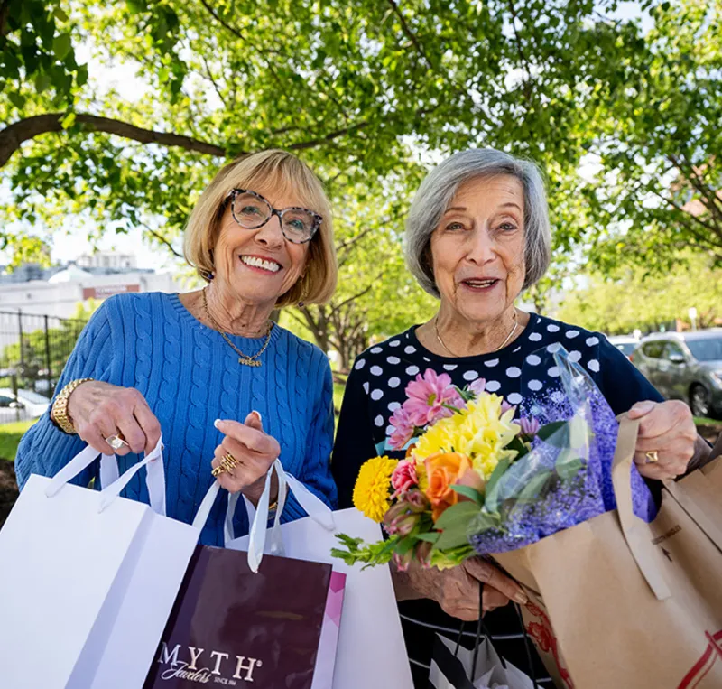 Two active senior women smiling holding shopping bags