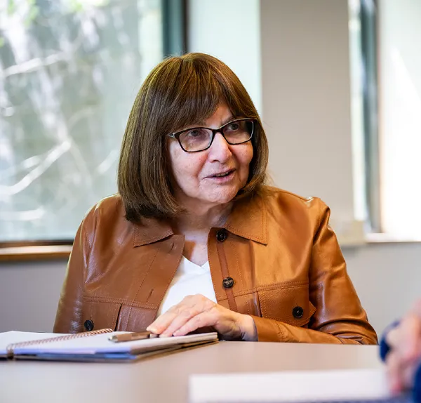 Woman conversing at a desk with a notepad and pen