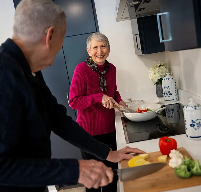 Woman smiling while cooking in the kitchen with her husband