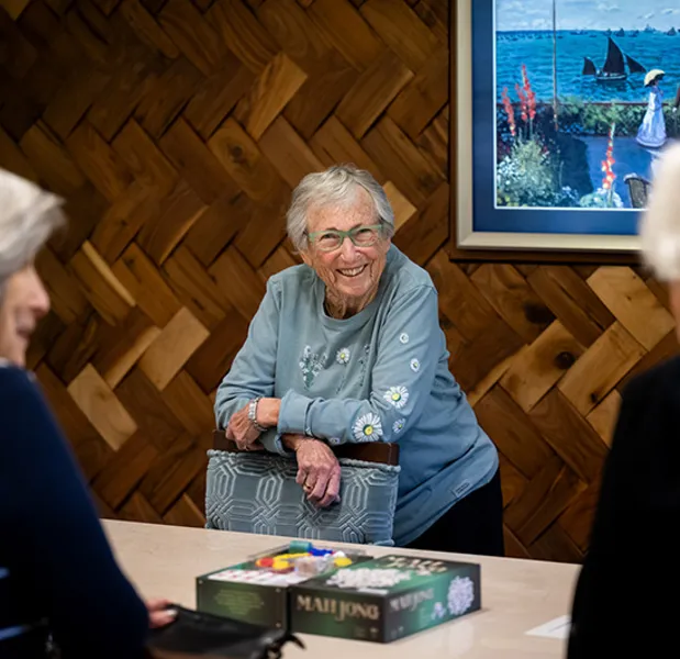 A woman standing at a table with board games smiling